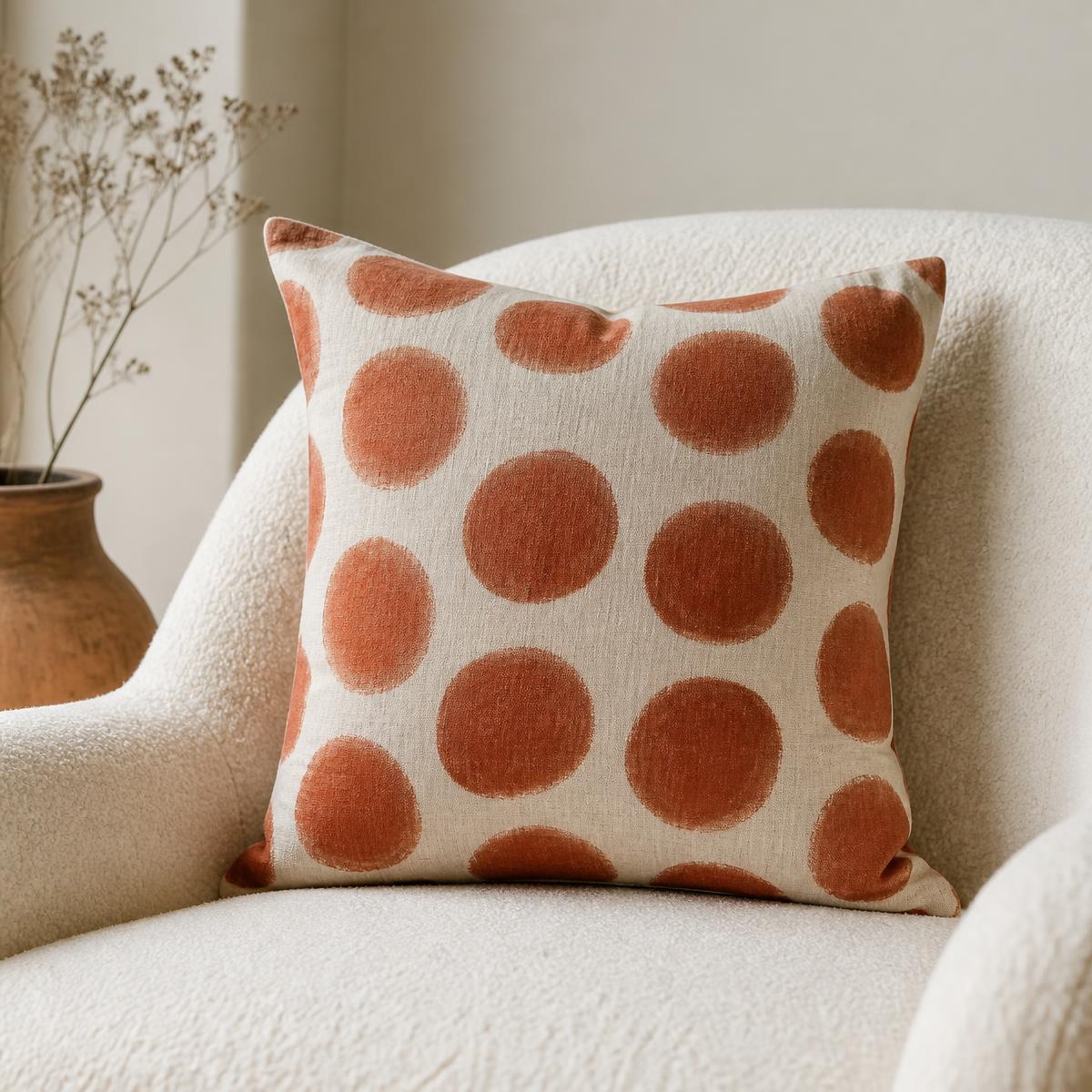 Linen cushion printed with rust clay spots on a cream boucle chair